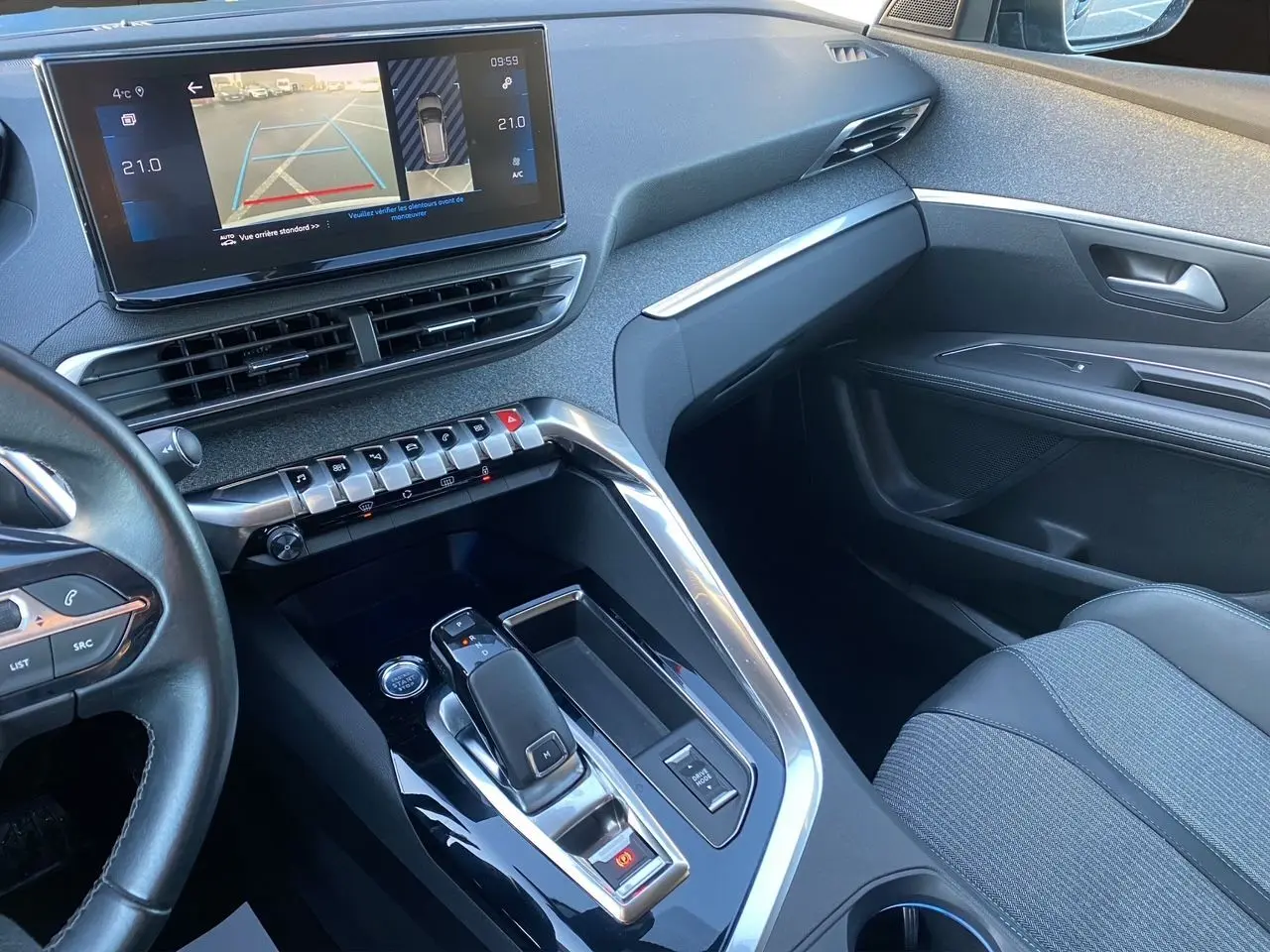 Vue intérieure côté passager du Peugeot 3008 Bleu Celebes 2021, avec console centrale moderne et écran tactile affichant la caméra de recul.