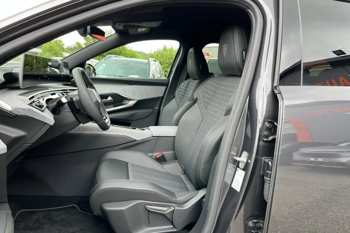 Vue intérieure côté conducteur du Peugeot 5008 gris titane, sièges avant en cuir avec logo Peugeot brodé sur les appuie-têtes.