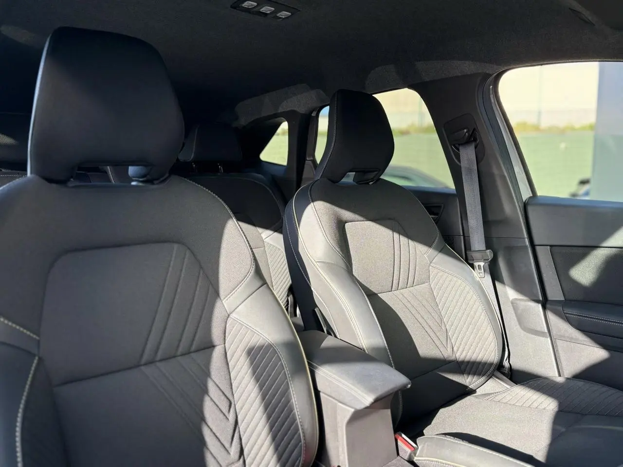 Vue intérieure des sièges avant en tissu gris avec coutures contrastées du Renault Symbioz E-Tech Full Hybrid 2025.