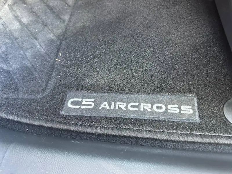Détail du tapis de sol noir avec logo C5 AIRCROSS en lettres blanches, intérieur du véhicule gris.