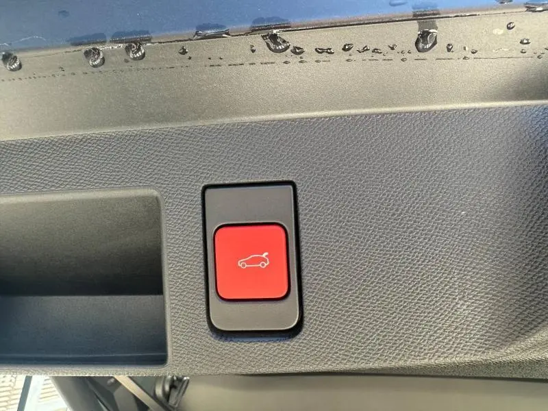 Bouton rouge d'ouverture électrique du coffre visible sur la garniture intérieure du hayon du Citroën C5 Aircross gris Platinium.