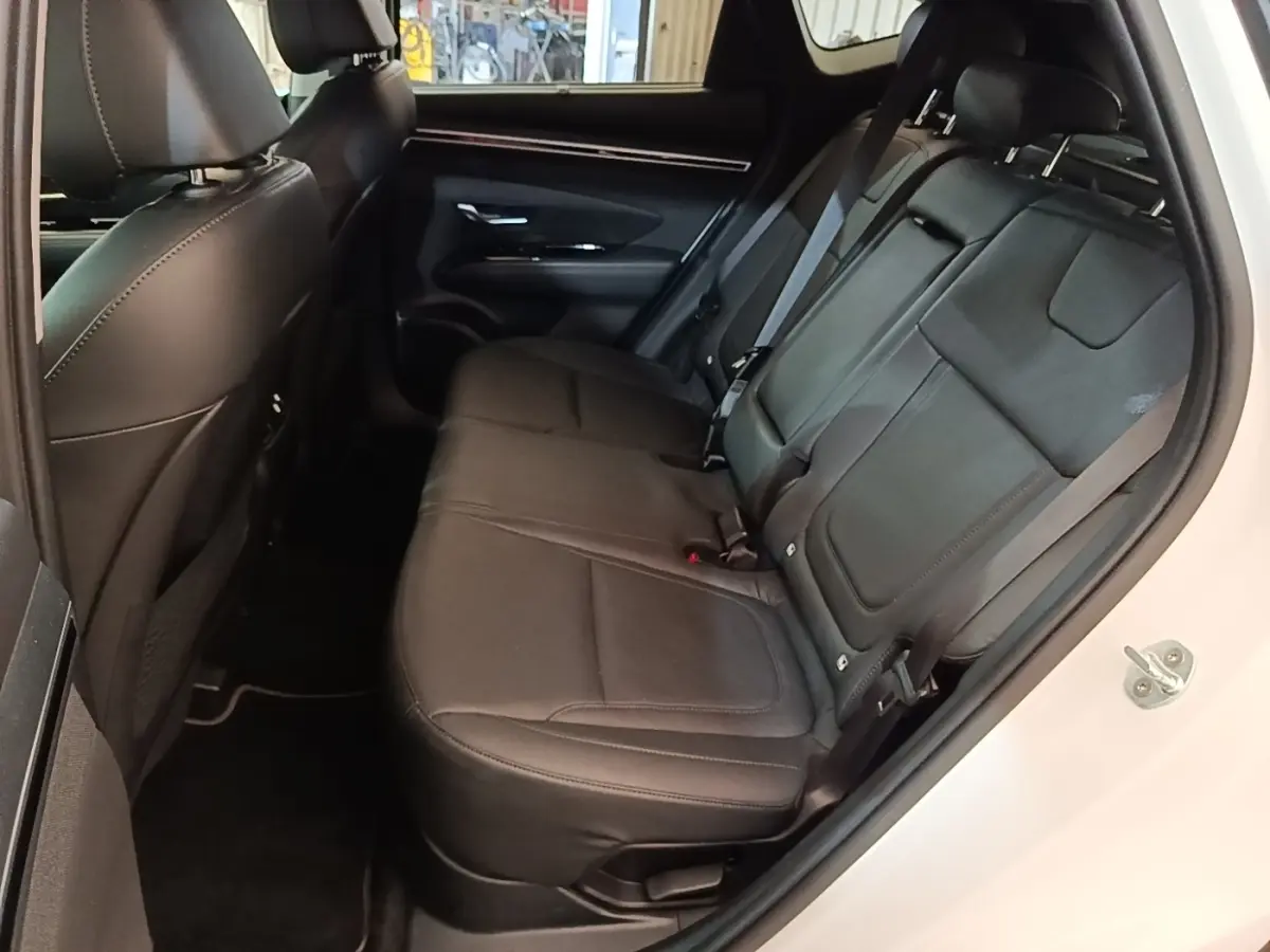 Vue intérieure côté droit des sièges arrière noirs en cuir du Hyundai Tucson blanc 2022, avec ceinture de sécurité visible.