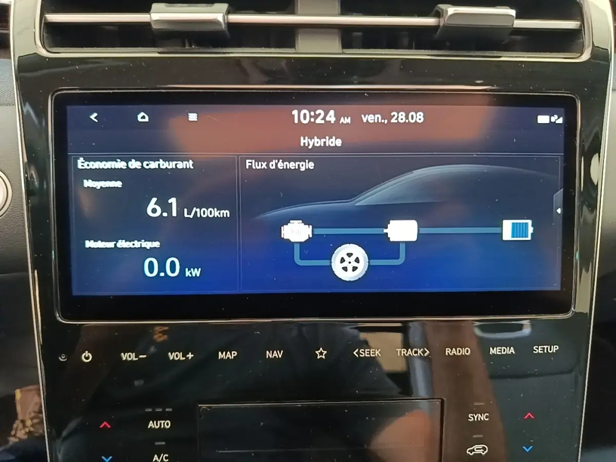 Écran tactile central affichant la consommation hybride et le flux d'énergie du Hyundai Tucson blanc, vue intérieure rapprochée.