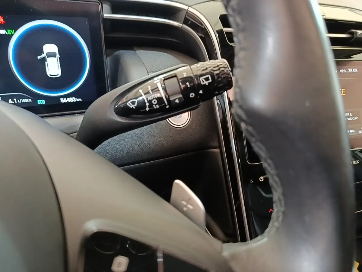 Gros plan sur le combiné d'instruments et le commodo d'essuie-glace du Hyundai Tucson blanc, intérieur noir.