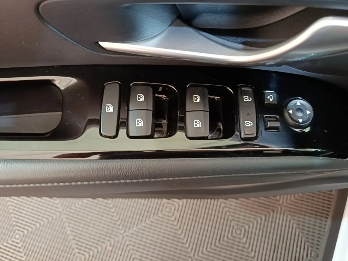 Gros plan sur les commandes de lève-vitres et rétroviseurs côté conducteur du Hyundai Tucson blanc 1.6 Hybrid 230 Executive 2022.