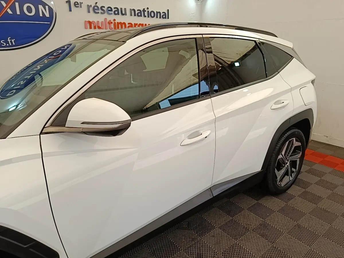 Vue côté gauche du Hyundai Tucson blanc 2022, mettant en valeur les lignes anguleuses et les jantes modernes.
