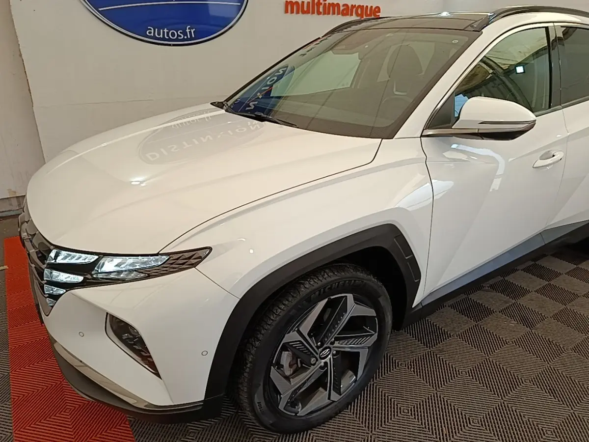 Vue 3/4 avant droit du Hyundai Tucson blanc avec phares LED et jantes alliage distinctives.