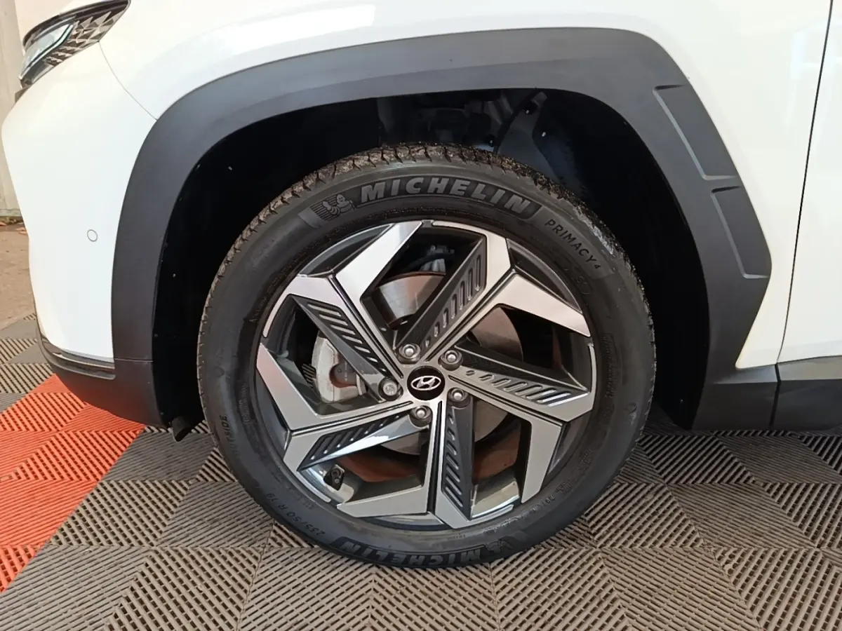 Gros plan sur la roue avant gauche du Hyundai Tucson blanc 2022 avec jante alliage au design moderne.
