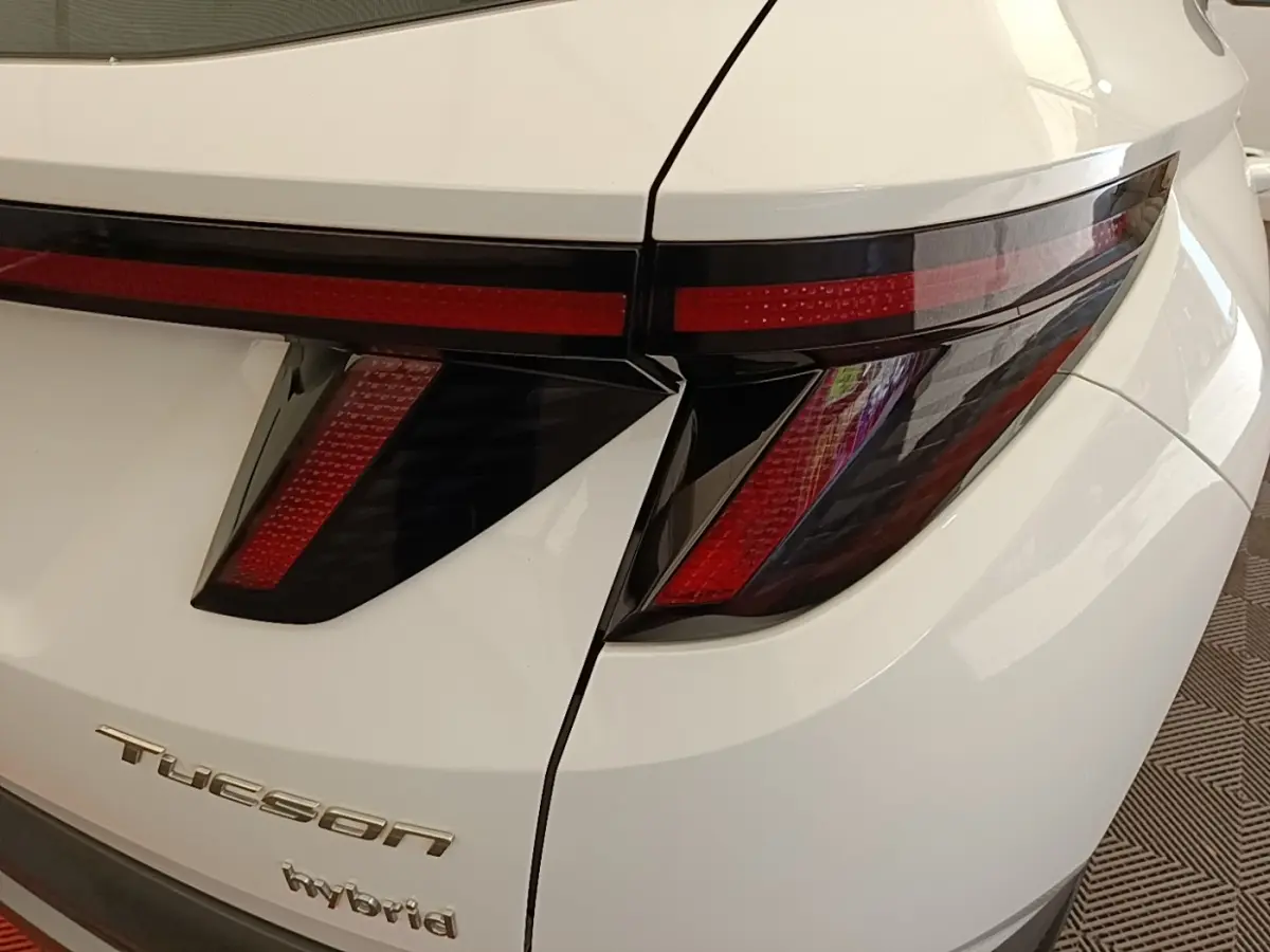 Gros plan sur l’arrière droit blanc d’un Hyundai Tucson Hybrid 2022, mettant en valeur ses feux arrière LED au design anguleux.
