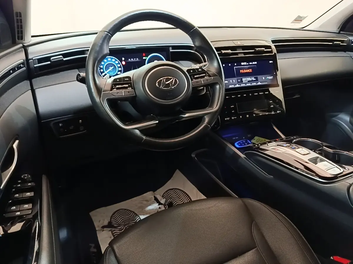 Intérieur du Hyundai Tucson 1.6 Hybrid 230 Executive 2022, vue du poste de conduite avec volant cuir et écran tactile central.