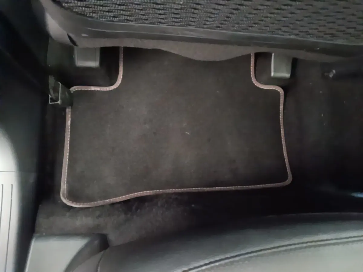 Plancher côté passager avec tapis noir bordé de surpiqûres marron dans un Hyundai Tucson blanc 2022.