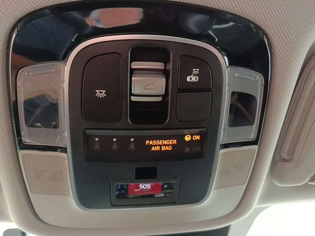 Vue en contre-plongée du panneau de commandes au plafond du Hyundai Tucson blanc, avec indicateur airbag passager et bouton SOS.