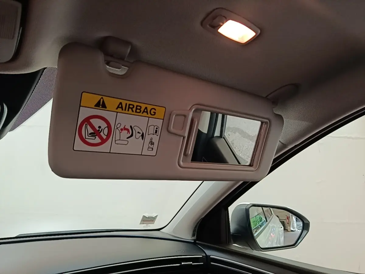 Détail intérieur du pare-soleil côté conducteur avec miroir et avertissement airbag dans un Hyundai Tucson blanc 2022.