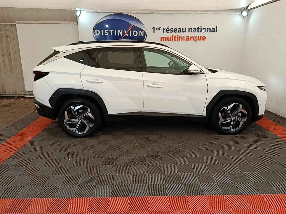 Vue de profil côté gauche d'un Hyundai Tucson blanc 2022 hybride, avec jantes alliage et toit ouvrant électrique.