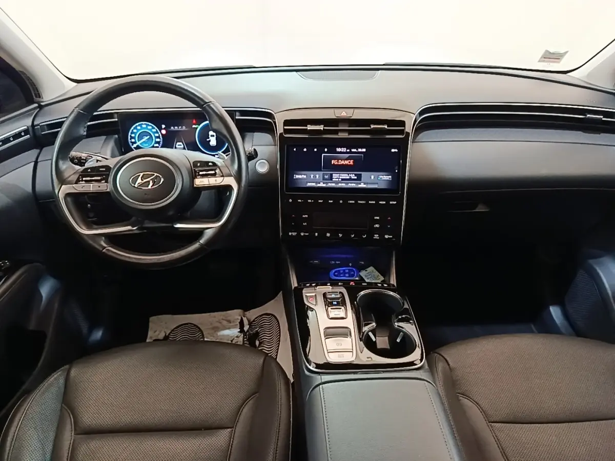 Vue intérieure avant du Hyundai Tucson 1.6 Hybrid 230 Executive 2022, tableau de bord noir avec écran tactile central et volant multifonctions.