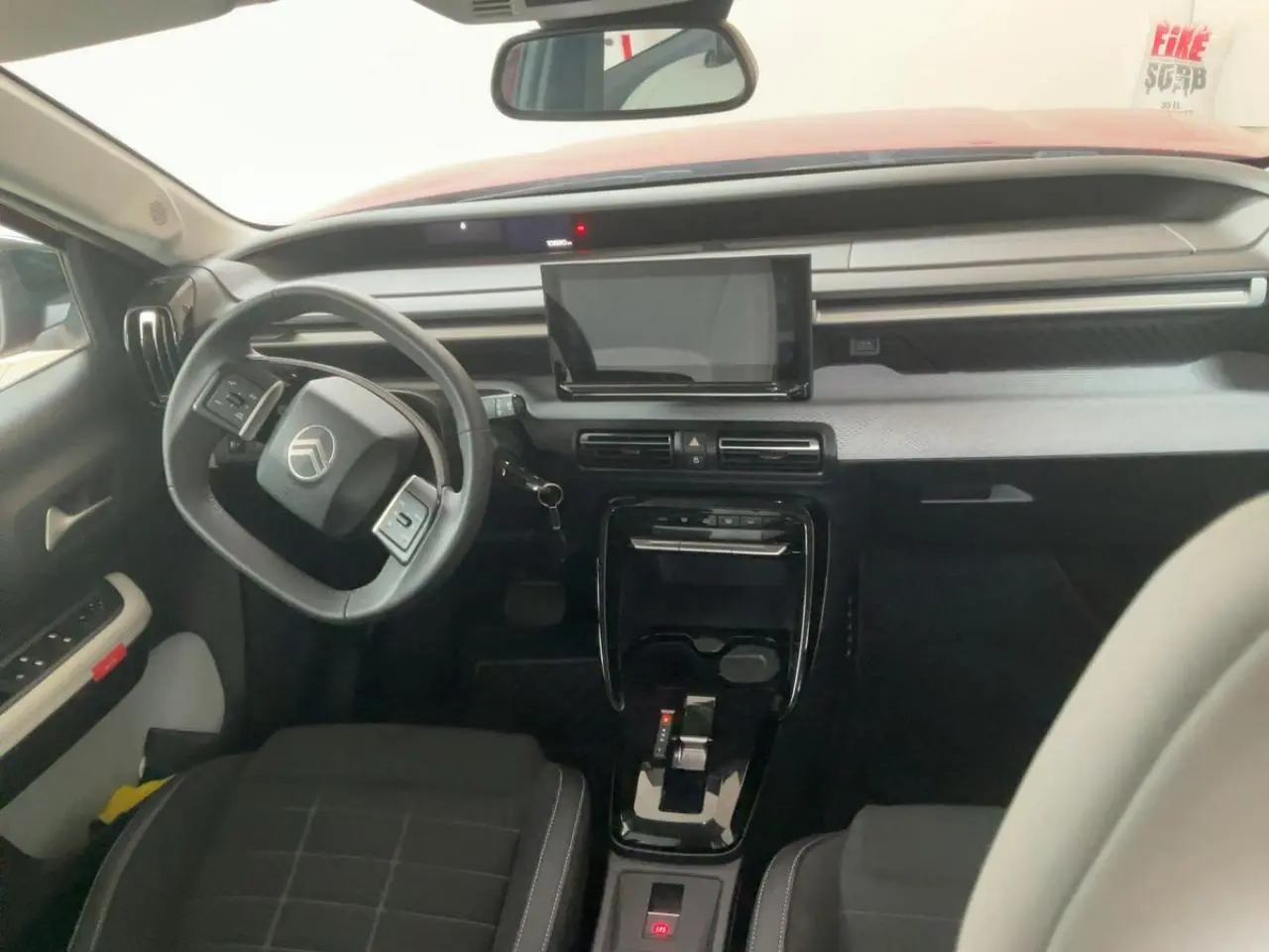 Vue intérieure avant de la Citroën C3 ë-113 Berline Max 2025, tableau de bord moderne avec écran tactile et volant multifonction.