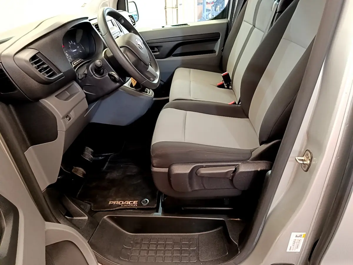 Vue intérieure côté conducteur du Toyota Proace Verso 2019 gris clair, montrant les sièges avant et le volant multifonctions.
