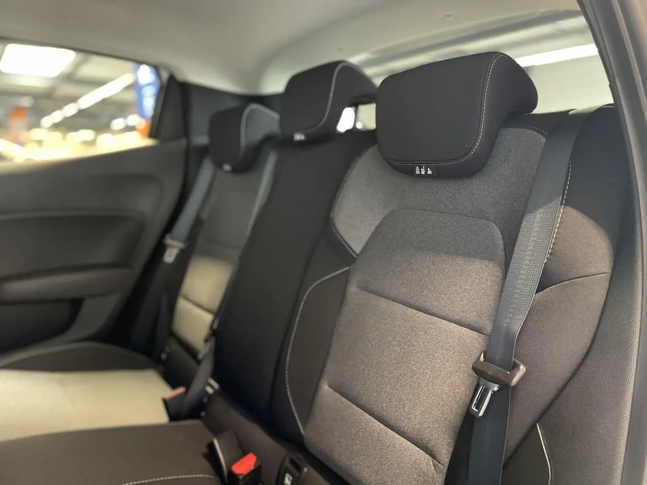Vue intérieure des sièges arrière gris foncé avec ceintures de sécurité d'une Renault Clio blanche 2025.