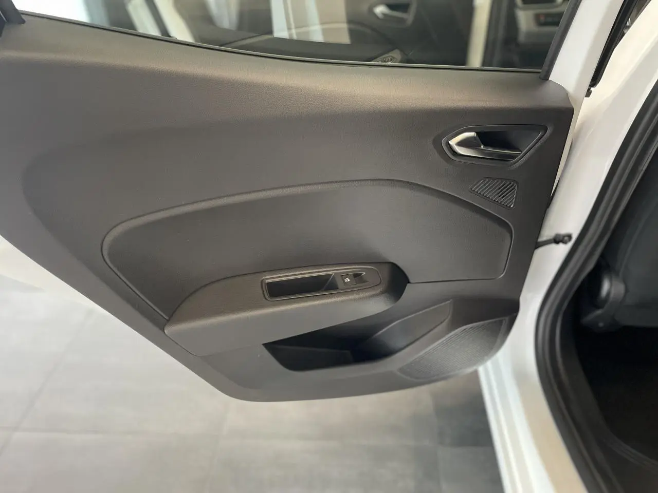 Porte intérieure côté arrière droit de la Renault Clio blanche 2025 avec commande de vitre électrique et poignée intégrée.