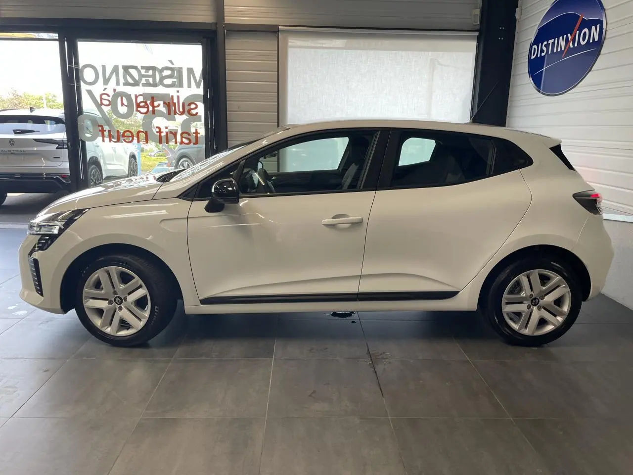 Profil côté gauche de la Renault Clio blanche 2025 en version Evolution, avec jantes 16 pouces et poignées couleur carrosserie.