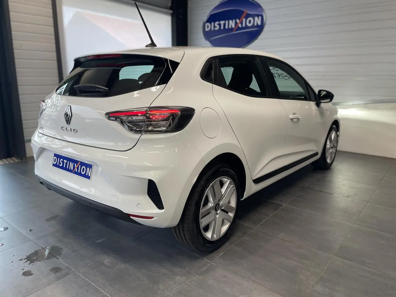 Renault Clio blanche vue 3/4 arrière droit en intérieur avec feux arrière LED et jantes alliage.