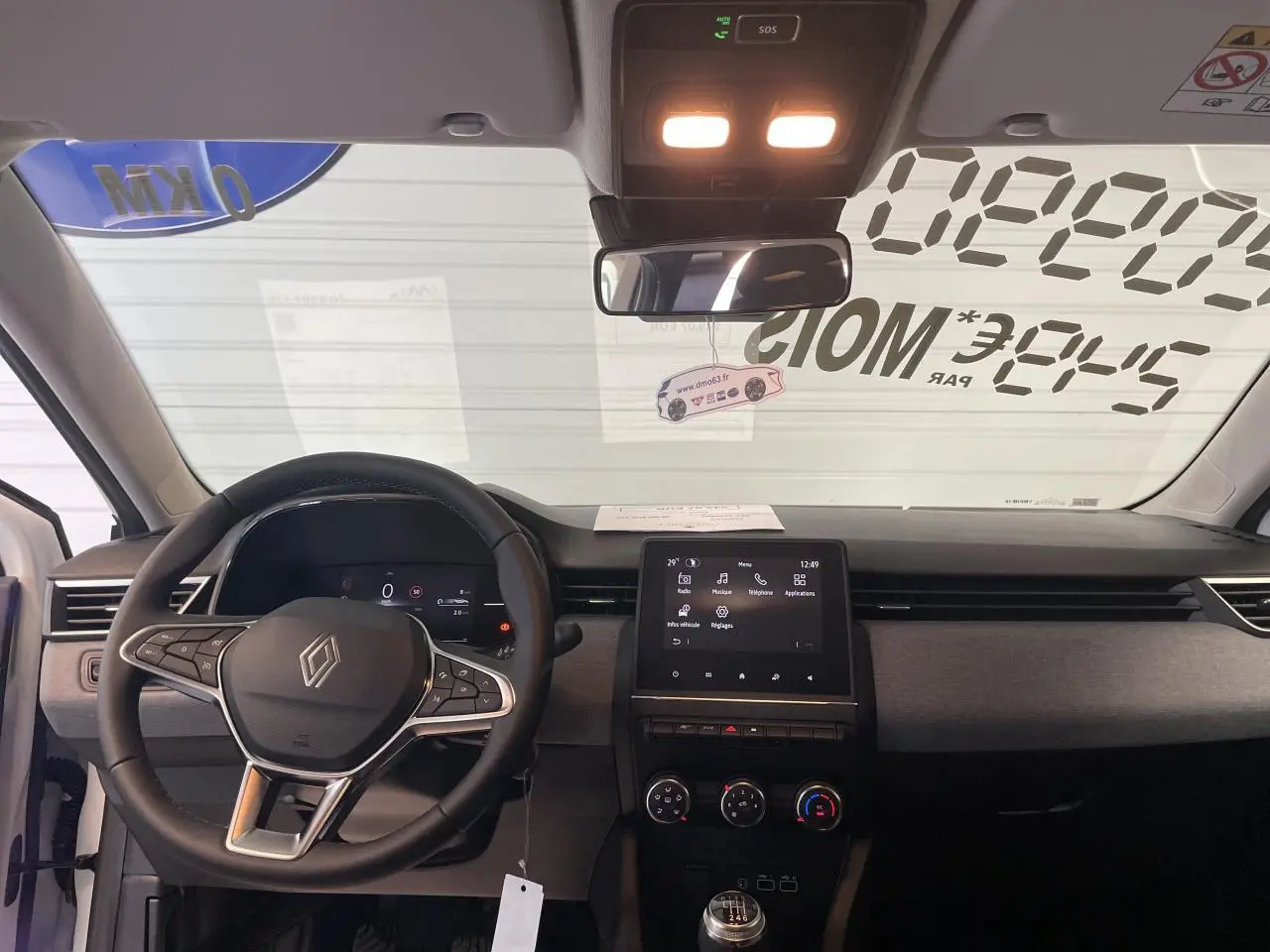 Vue intérieure avant de la Renault Clio 2025, tableau de bord noir avec écran tactile et volant multifonction.