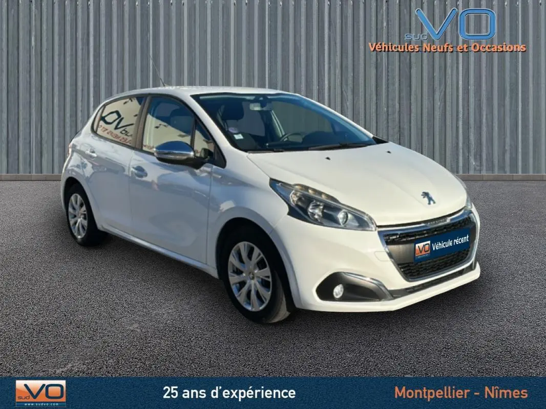 Peugeot 208 blanc vue 3/4 avant droit, jantes 15 pouces classiques, phares et antibrouillards visibles, arrière légèrement masqué.