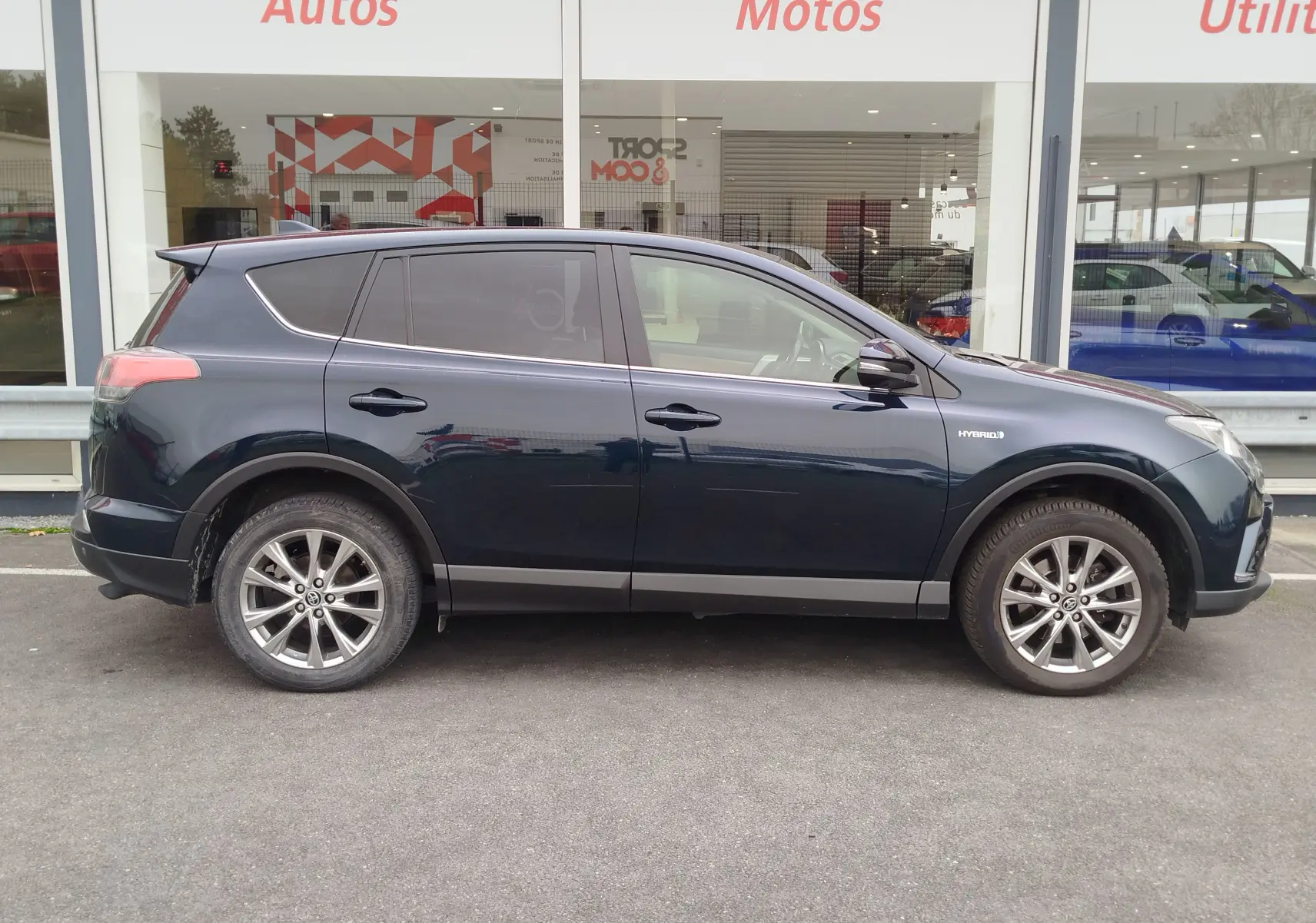 Profil côté gauche d'un Toyota RAV4 noir cobalt hybride de 2017 avec jantes alliage et vitres teintées.