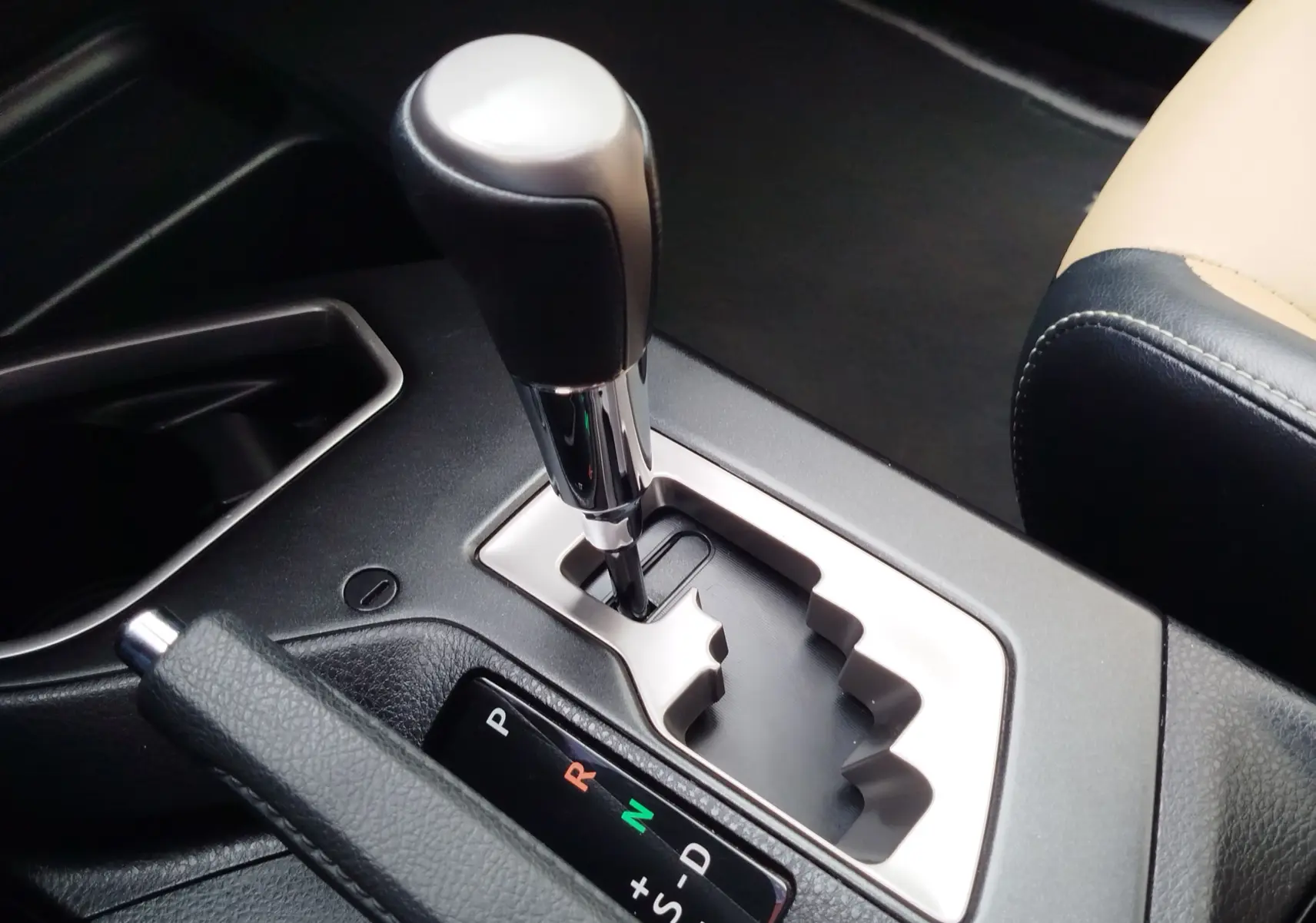 Gros plan sur le levier de vitesses automatique chromé et noir du Toyota RAV4 2017, intérieur beige et noir.