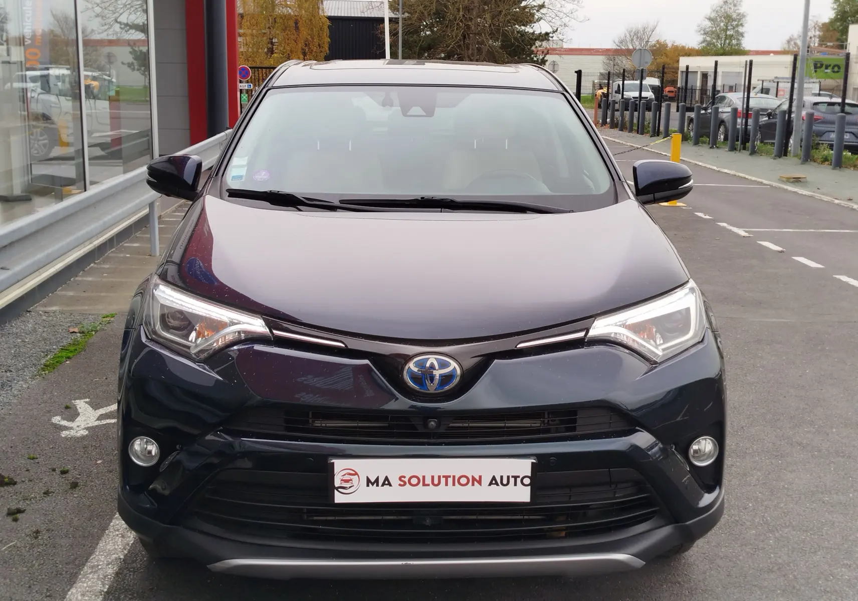 Vue de face d'un Toyota RAV4 197 Hybride Lounge AWD CVT noir cobalt, avec phares LED et calandre distinctive.