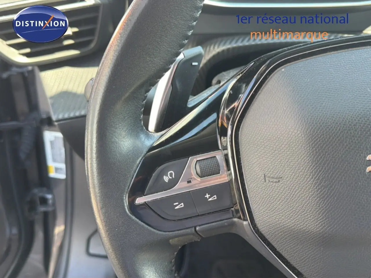 Gros plan sur le volant noir de la Peugeot 2008 1.2 PureTech 130 Allure, montrant les commandes audio et de volume.