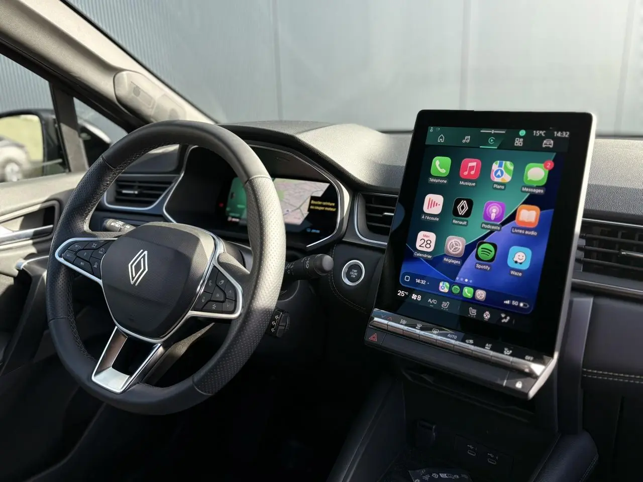 Vue intérieure côté conducteur du Renault SYMBIOZ 2025, avec volant noir et grand écran tactile central allumé.