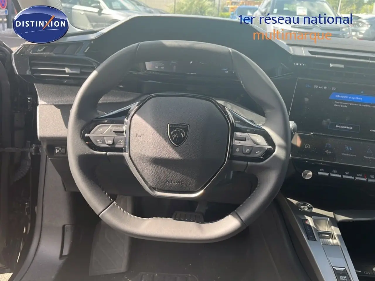 Vue intérieure centrée sur le volant noir de la Peugeot 308 Hybrid 145ch 2025 avec tableau de bord et écran tactile.