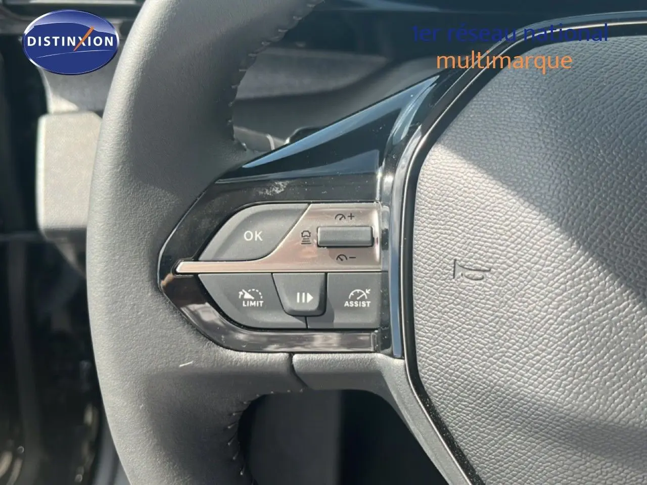 Gros plan sur les commandes à gauche du volant cuir noir de la Peugeot 308 Hybrid 145ch 2025.