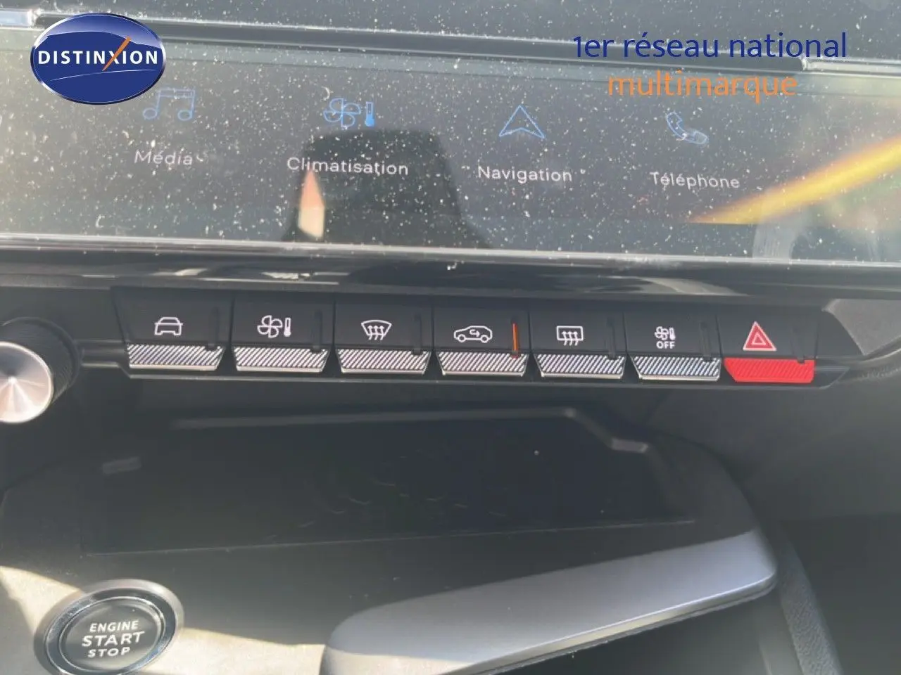 Vue rapprochée du tableau de bord de la Peugeot 308 Hybrid 2025, montrant les commandes tactiles et boutons de climatisation et sécurité.