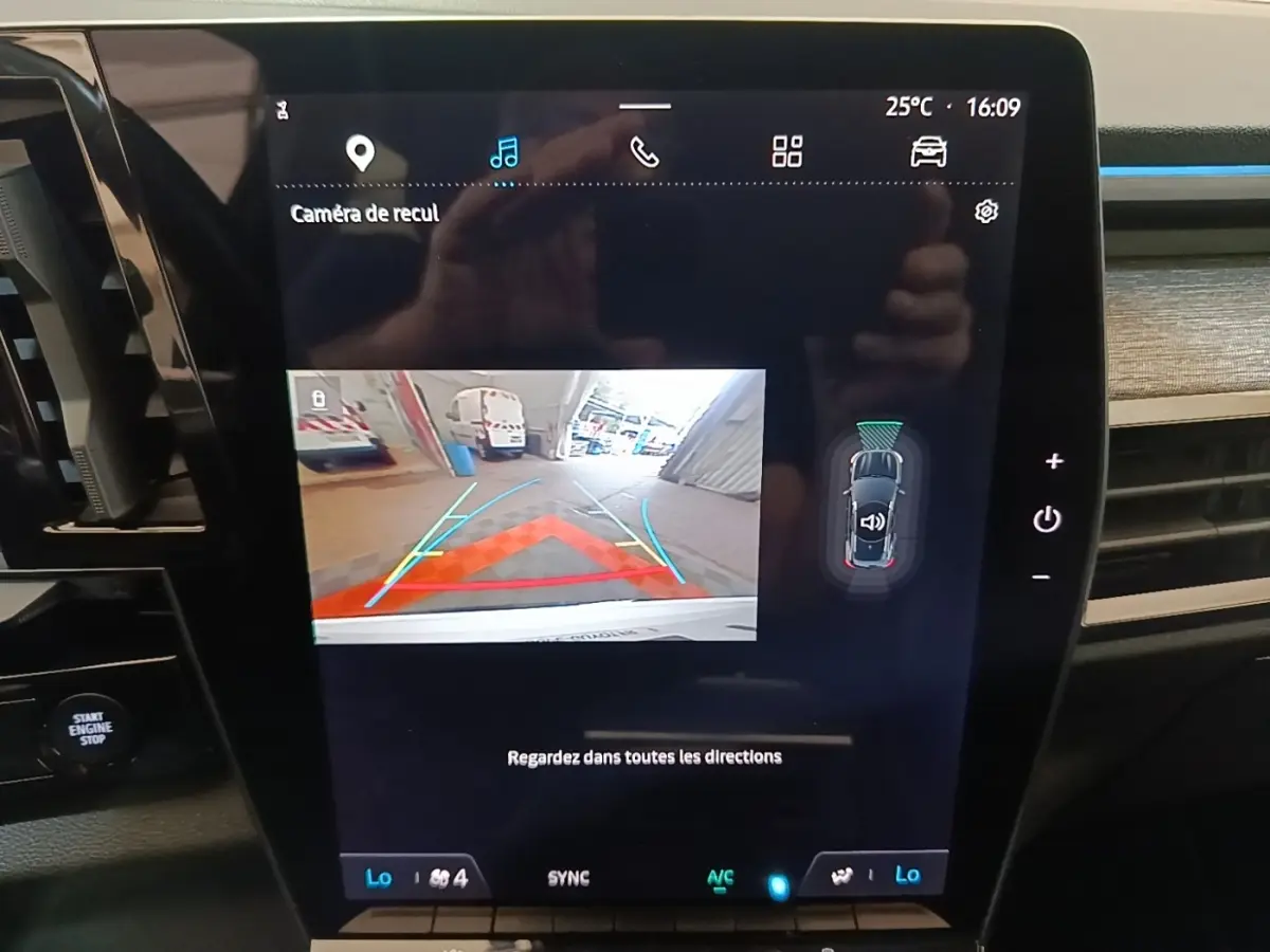 Écran tactile central du Renault Austral blanc montrant la caméra de recul et l’aide au stationnement en intérieur.