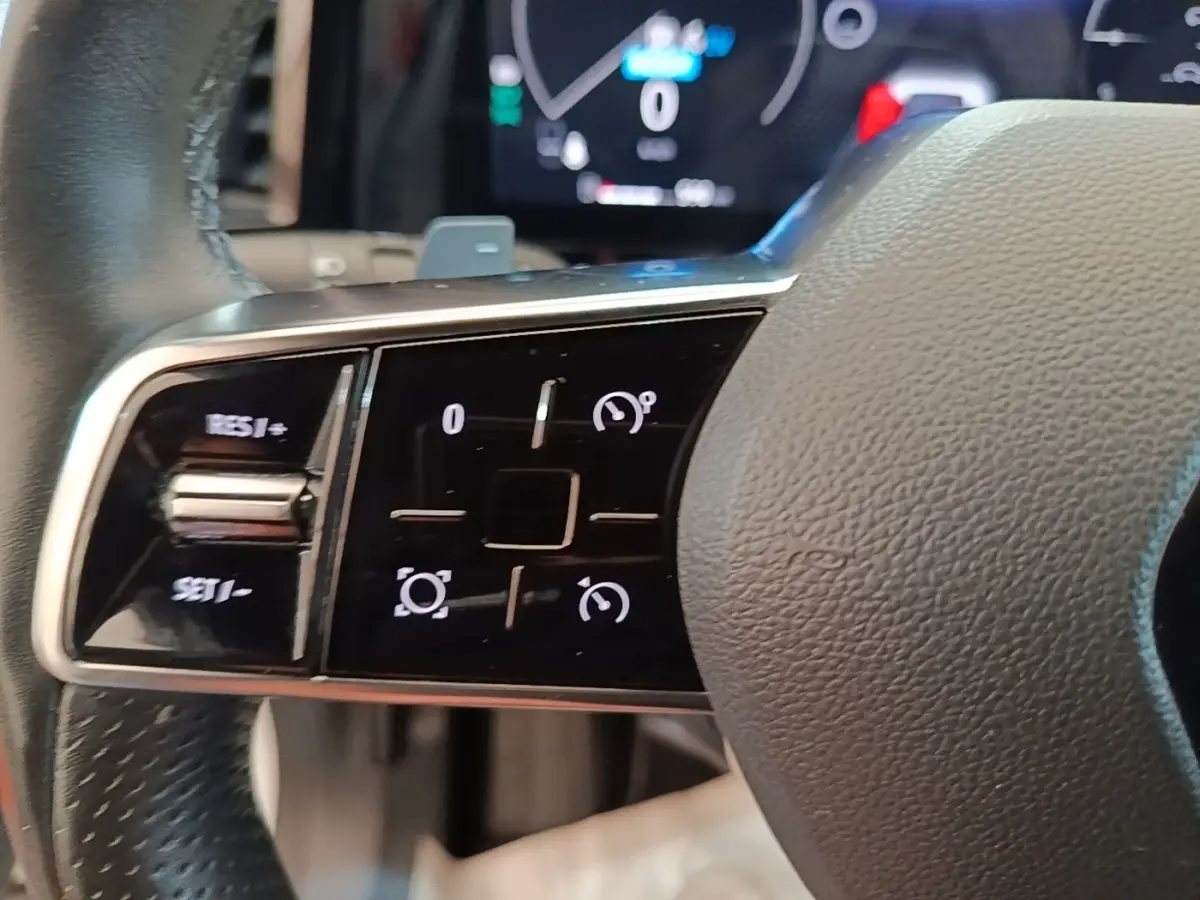 Gros plan sur les commandes multifonctions du volant cuir du Renault Austral blanc, avec affichage numérique en arrière-plan.