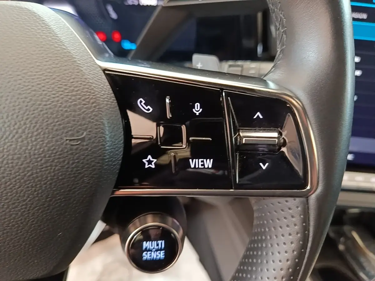 Gros plan sur le volant cuir du Renault Austral blanc 2023, avec commandes multifonctions et bouton Multi Sense éclairé.