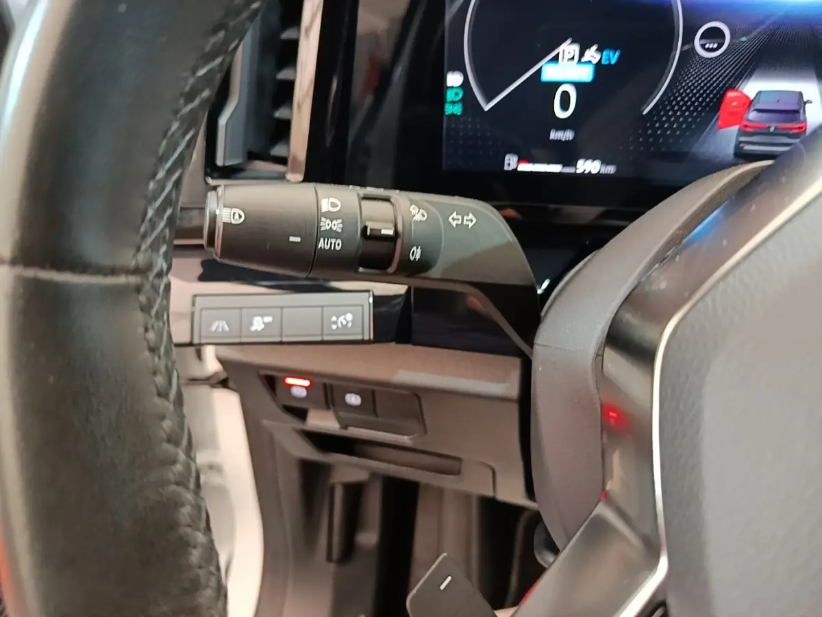 Gros plan sur le volant cuir et la commande des phares du tableau de bord du Renault Austral blanc hybride 2023.
