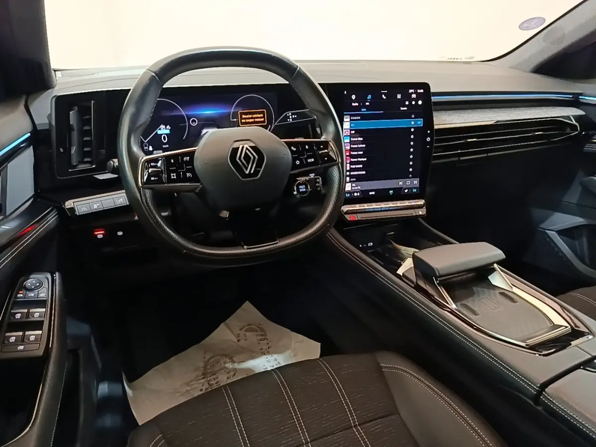 Vue intérieure du poste de conduite du Renault Austral blanc, avec volant cuir et grand écran tactile vertical.