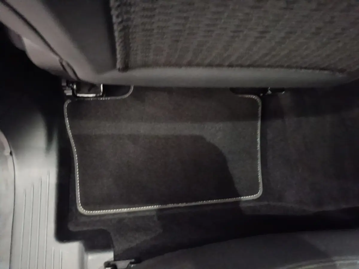 Détail du tapis de sol noir sous le siège arrière du Renault Austral blanc version Techno E-Tech Hybride 200.