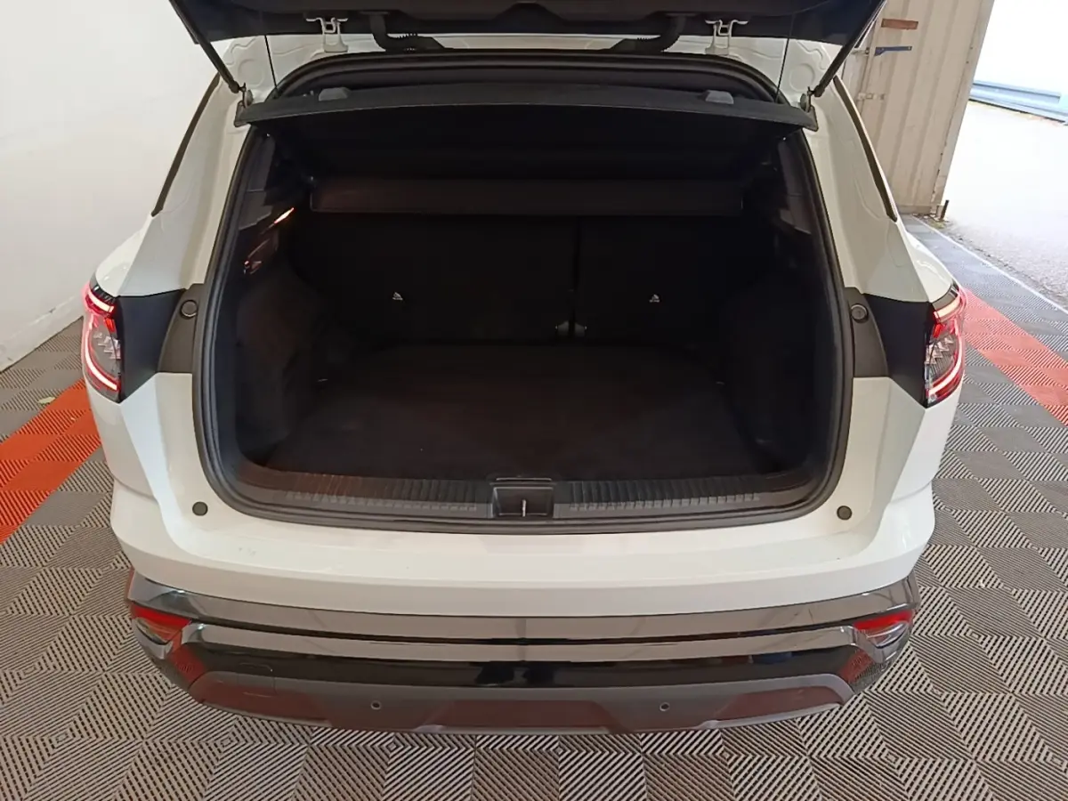 Coffre ouvert d’un Renault Austral blanc vu de l’arrière, montrant l’espace de chargement et les feux arrière LED allumés.