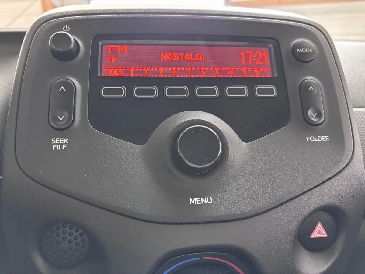 Gros plan sur l’autoradio noir de la Toyota Aygo 2020, affichant la radio FM sur fond rouge.