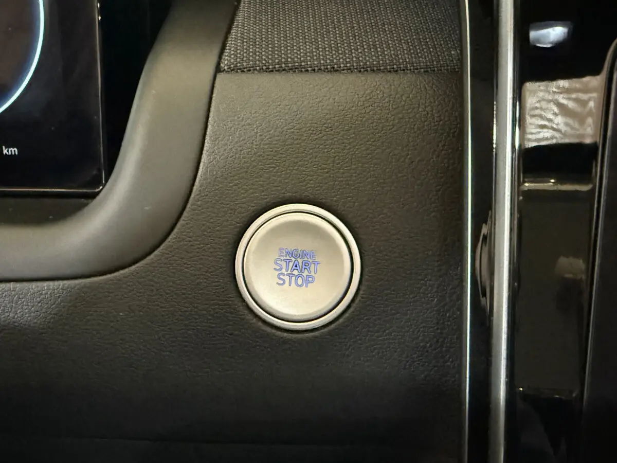Bouton démarrage moteur circulaire argenté sur tableau de bord noir du Hyundai Tucson hybride 2021.
