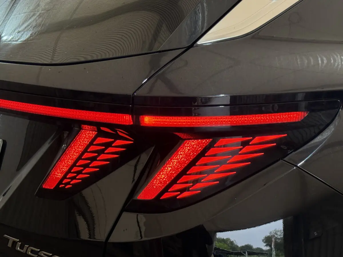 Feu arrière droit allumé du Hyundai Tucson noir 2021, soulignant son design lumineux distinctif en forme de flèches.