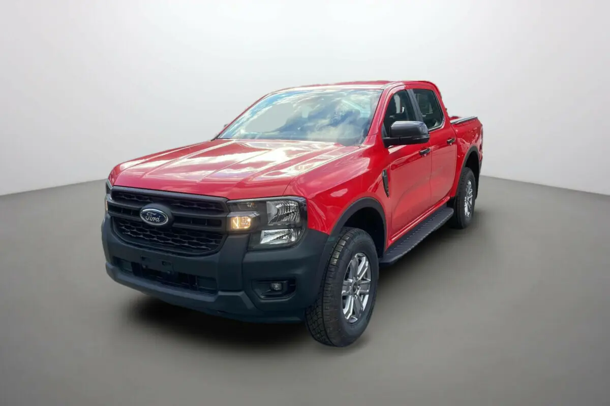 Ford Ranger 2025 rouge racing en 3/4 avant droit, avec calandre noire et phares allumés sur fond neutre.