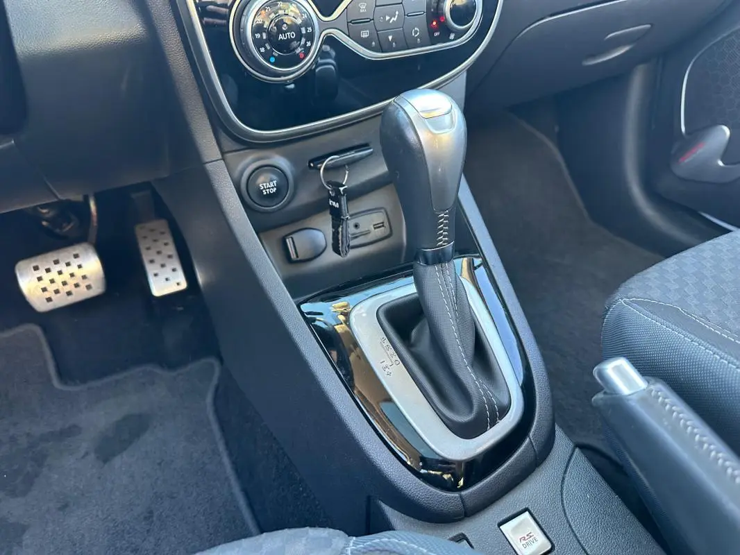Gros plan sur la console centrale de la Renault Clio IV TCe 120 GT EDC blanche, montrant levier de vitesse automatique et commandes.
