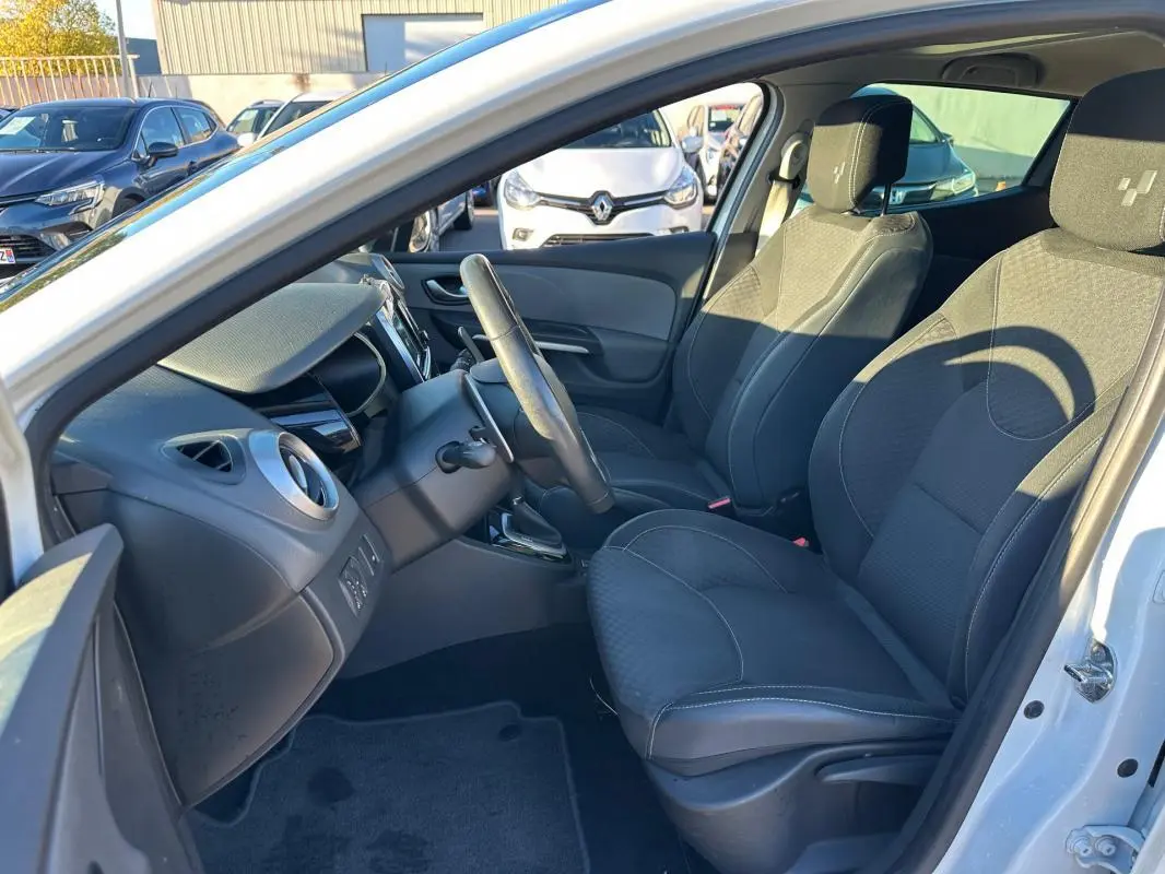 Intérieur avant droit d'une Renault Clio IV blanche, sièges noirs avec appuis-tête et volant cuir visible.