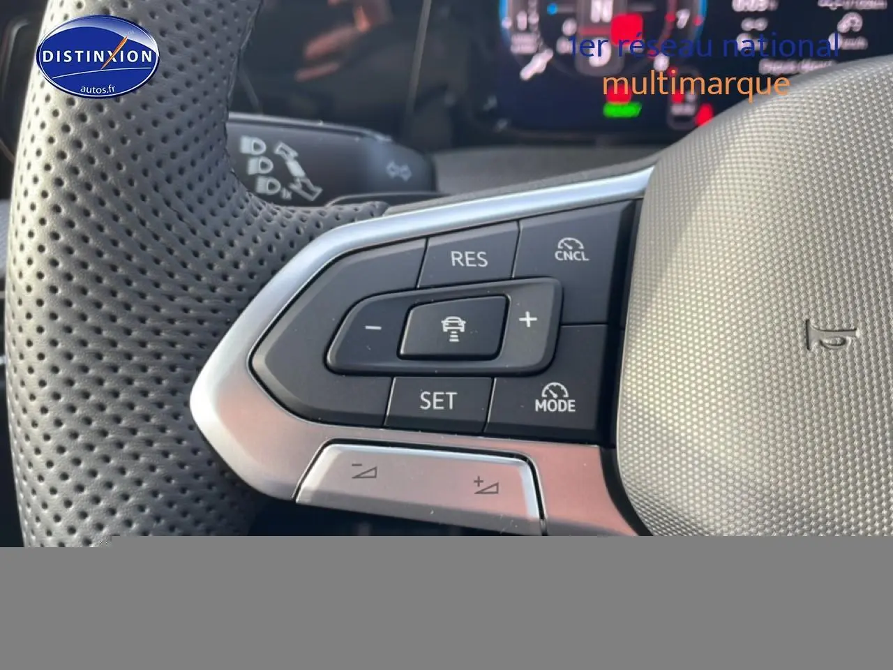 Gros plan sur les commandes du volant cuir perforé de la Volkswagen Golf gris, avec régulateur de vitesse et aides à la conduite.