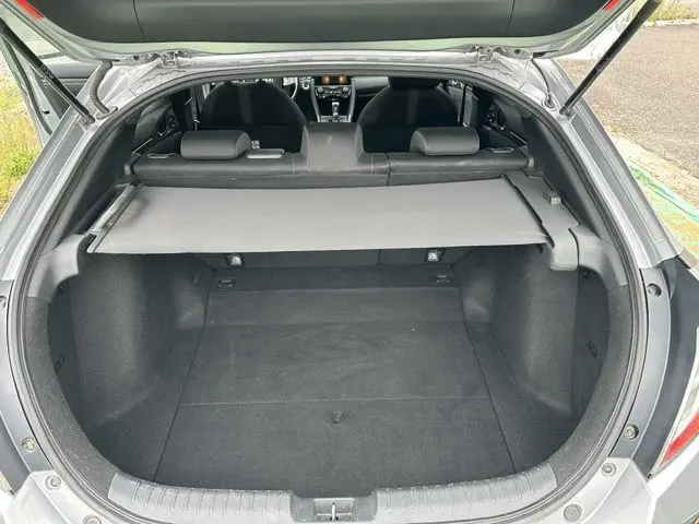 Coffre ouvert d'une Honda Civic grise vue de l'arrière, montrant l'espace de chargement et l'intérieur noir.